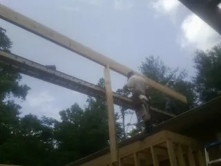 Carpenter setting a ridge beam over a new addition frame — Ice Dam Removal by Roofing Brothers in Pierce