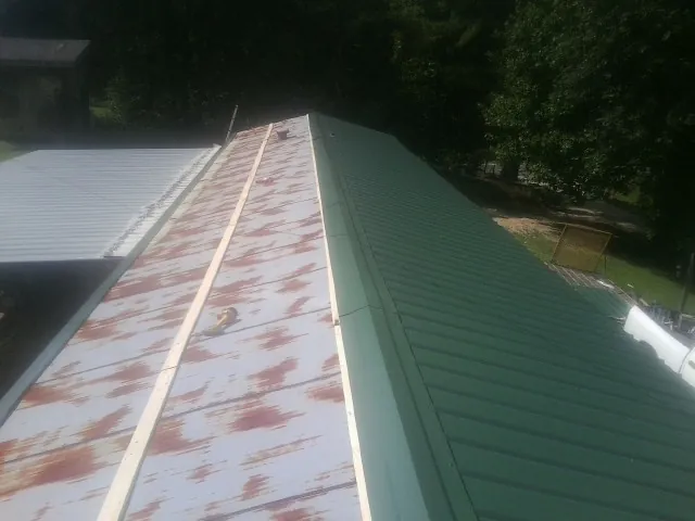 Old rusted panels beside newly installed green metal roofing — Wind Damage Roof Repair by Roofing Brothers in Pierce